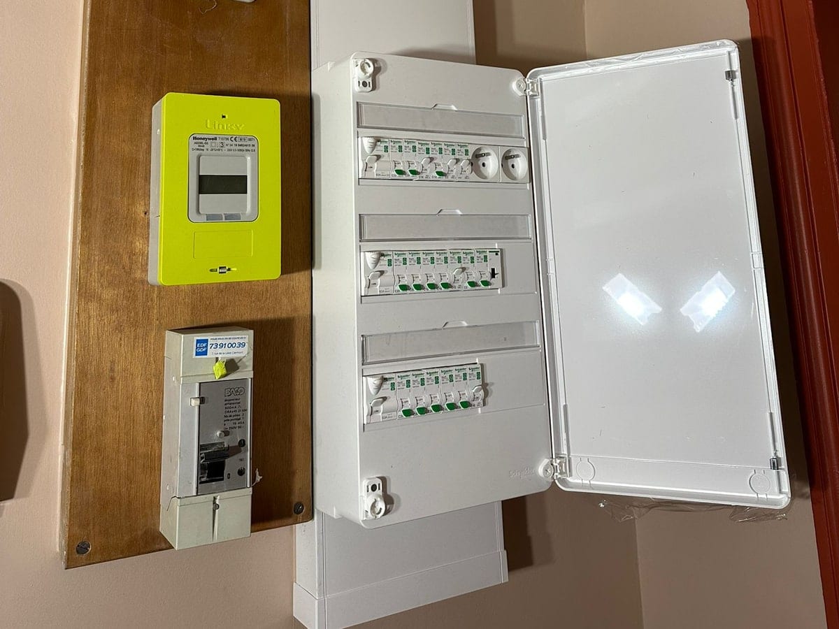 Tableau électrique neuf ouvert à côté du compteur Linky dans un appartement ancien